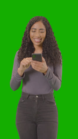 Vertical-Video-Woman-Looking-At-Mobile-Phone-And-Celebrating-Good-News-Against-Green-Screen-4